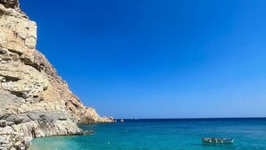 Un paysage côtier avec une eau turquoise et limpide, une falaise rocheuse et un bateau sur la mer.