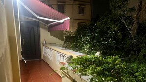 Een balkon met betegelde vloer, een rode luifel en een witte balustrade.