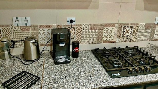Een keuken met een gasfornuis, een koffiezetapparaat, een waterkoker en een voorraadbus.