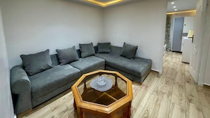 Een moderne woonkamer met een hoekbank, een houten salontafel en inbouwverlichting.
