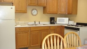 Une cuisine avec des meubles de rangement en bois, un four à micro-ondes, une cuisinière et une table à manger avec des chaises.