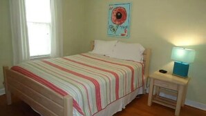 Une chambre à coucher avec un lit, une table de chevet avec une lampe et une fenêtre.