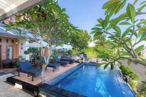 A swimming pool with lounge chairs and a tree. - D' Artha Cottage (Bali)
