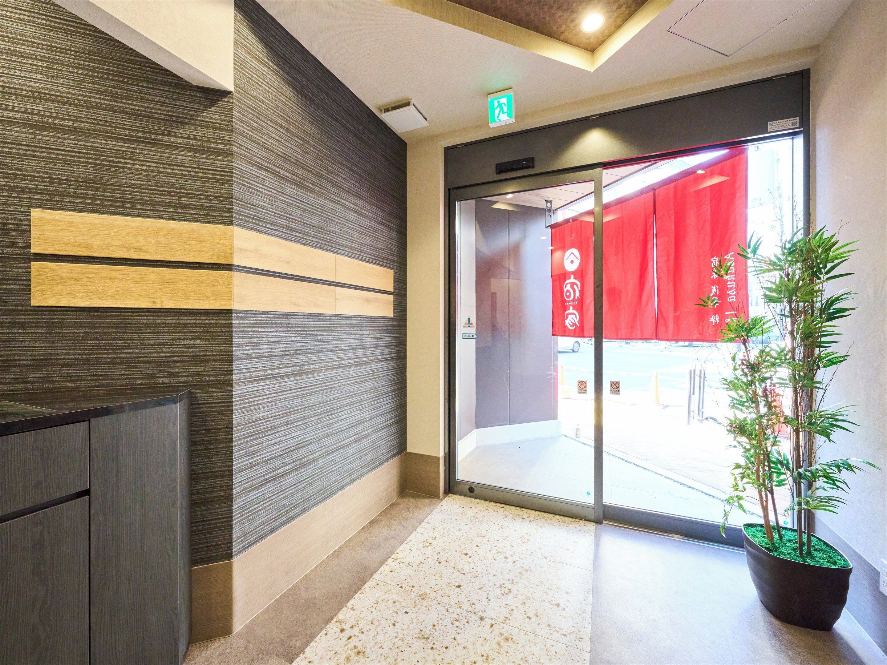 A reception area with a modern design, including a reception desk, a wall with horizontal wooden panels, and a potted plant.