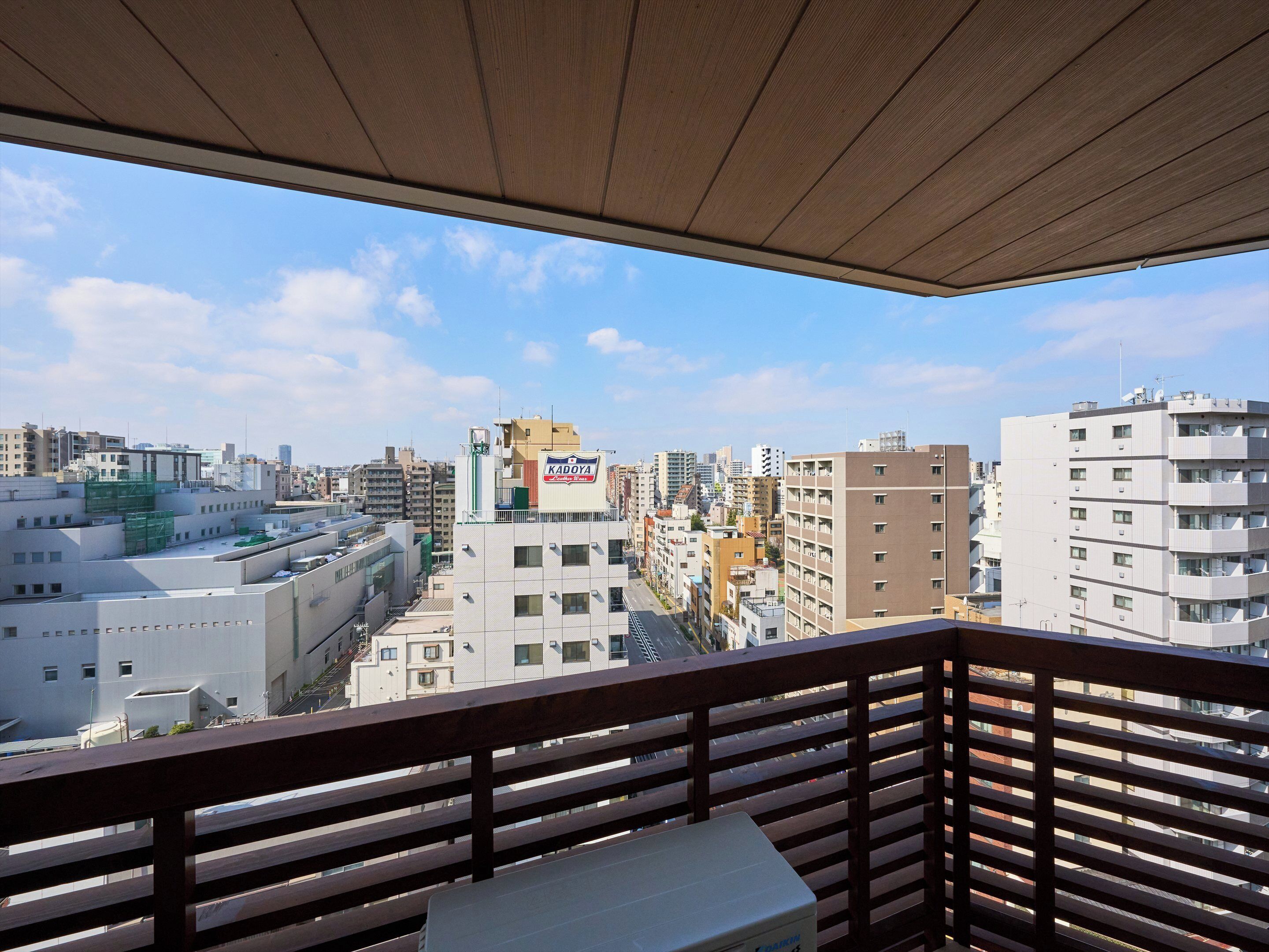 A balcony with a view of a cityscape, including a building with a 'KADAYA' sign.