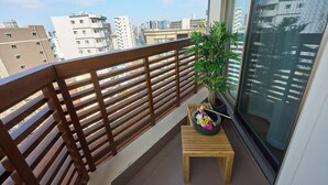 En balkon med gelænder af træ, et lille træbord og en potteplante.