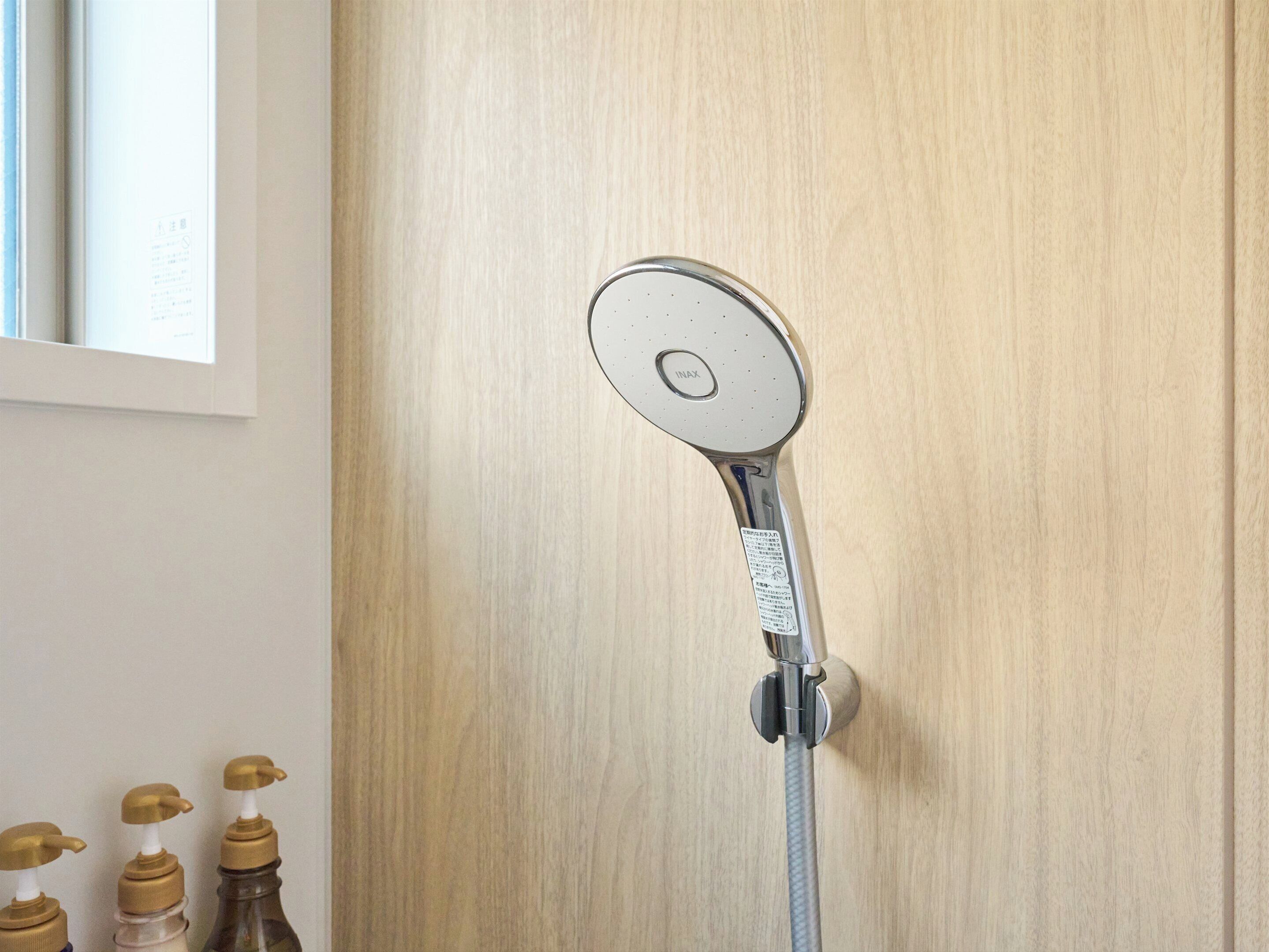 Un cabezal de ducha instalado en una pared, con un fondo de panel de madera.
