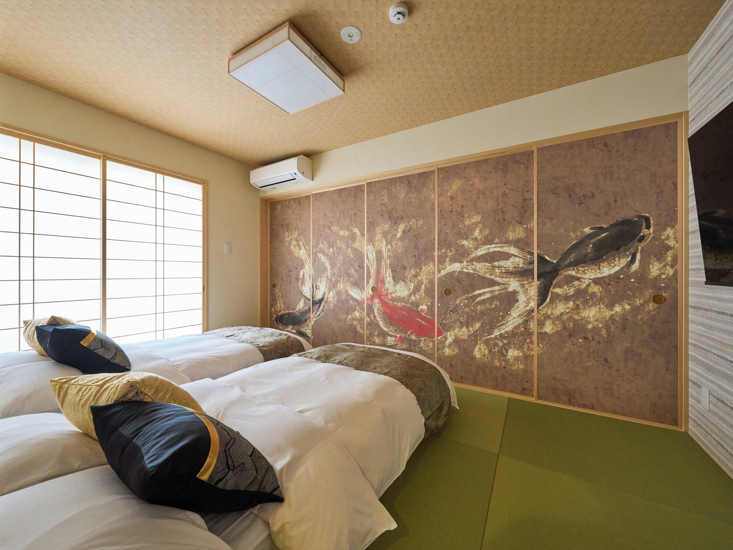A hotel room with two beds, a large artwork on the wall, and a view of the outside through a window.