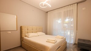 A modern bedroom with a large bed, a bedside table, and a hanging light fixture. - Designer Apartment in the Pines San Pietro (Ishëm)