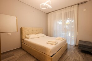 A modern bedroom with a large bed, a bedside table, and a hanging light fixture. - Designer Apartment in the Pines San Pietro (Ishëm)