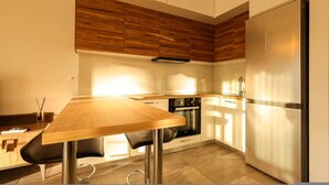 A modern kitchen with a wooden countertop, stainless steel appliances, and a built-in oven. - Designer Apartment in the Pines San Pietro (Ishëm)