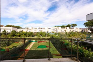 A residential area with a view of apartment buildings, a green lawn with colorful patterns, and a clear sky. - Family Beach Villa w Garden (Ishëm)