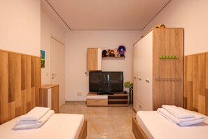 A hotel room with two beds, a TV, wooden wardrobes, and a shelf with toys. - Sanpietro Vacation Apartment 048 (Ishëm)