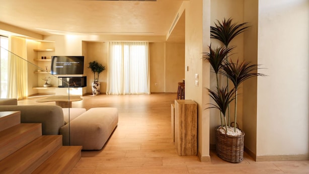 Una sala de estar moderna con un sofá, televisor y una escalera que sube a un nivel superior.