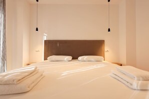 A modern hotel room with a large bed, two bedside tables, and a headboard.