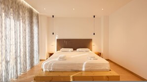 Un dormitorio moderno con una cama grande, plataforma de madera y un ventanal con cortinas.