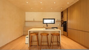 Una cocina moderna con una isla central, taburetes de madera y armarios empotrados.