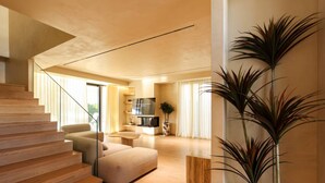 Una sala de estar moderna con una escalera, un televisor de pantalla plana y una planta grande.