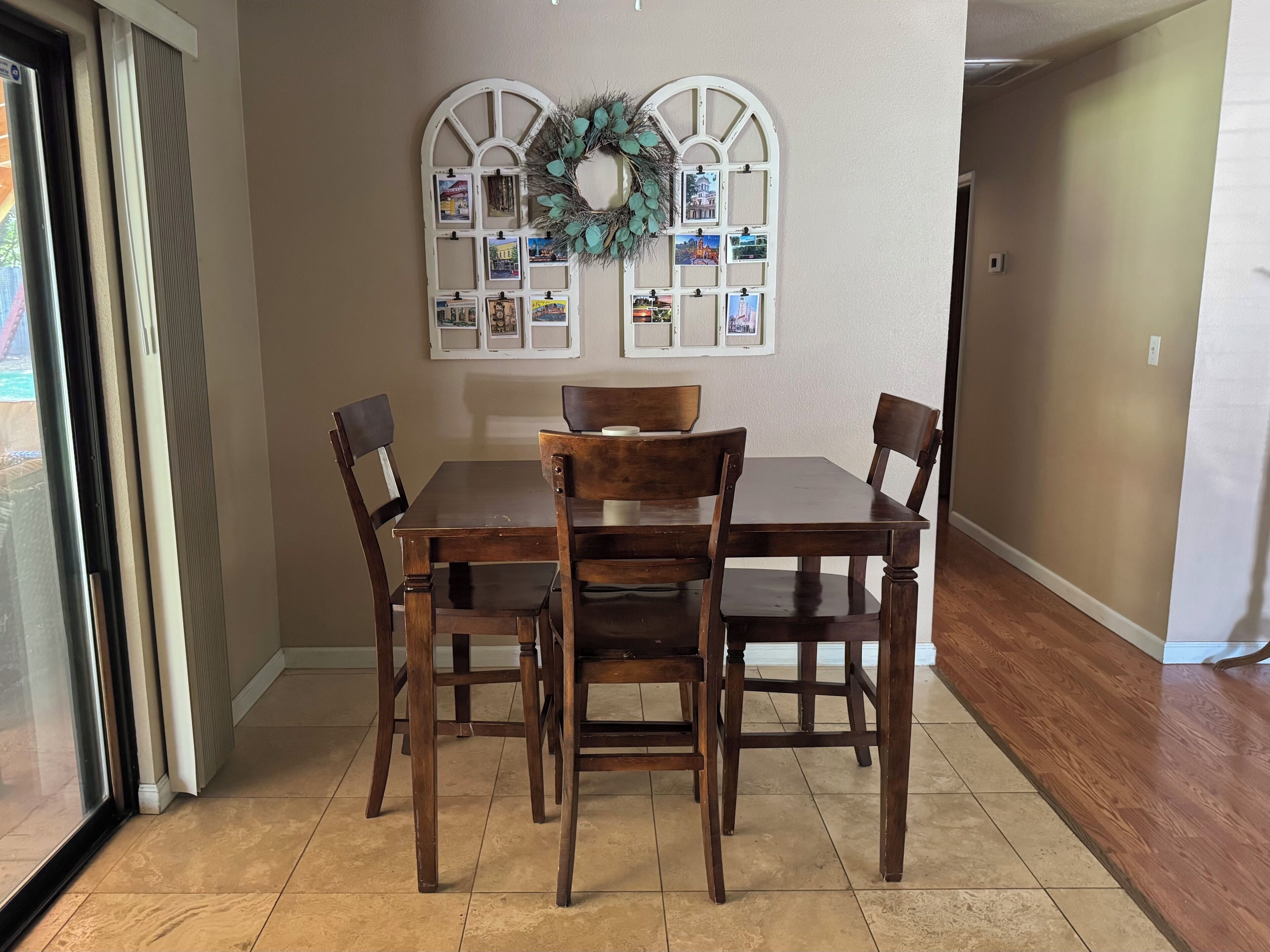 Uma área de refeições com uma mesa e quatro cadeiras, uma guirlanda decorativa e uma parede com fotografias.