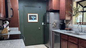 Una cucina con mobili in legno scuro, un frigorifero in acciaio inossidabile, un piano di lavoro in granito e un pavimento piastrellato.
