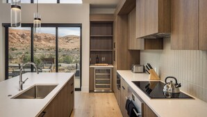 A modern kitchen with a large island, built-in oven, and a view of a desert landscape. - Luxury Moab Casita with Resort Pool, Hot Tub & Bunk Room (Moab)