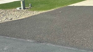 Un edificio con garaje, fachada de piedra y césped verde.