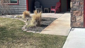 Una casa de dos pisos con fachada de piedra, techo rojo y un porche cubierto con mobiliario exterior.