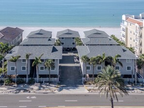 Ein Strandhotel mit mehrstöckigen Gebäuden, einer zentralen Treppe und Palmen.