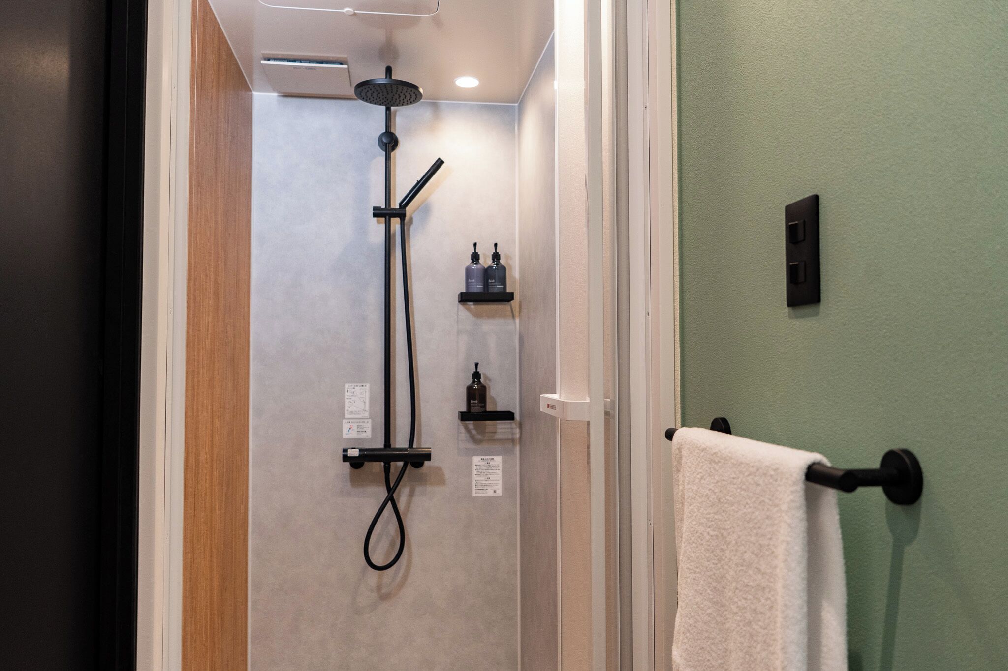 A bathroom with a shower, a towel rack, and a shelf with toiletries.
