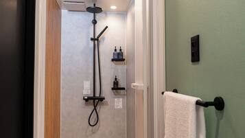 A bathroom with a shower, a towel rack, and a shelf with toiletries.