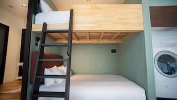 Habitación con literas, una escalera de madera, lavadora y pared verde claro.