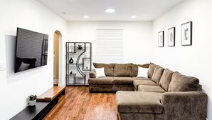 A modern living room with a sectional sofa, a flat-screen TV, and a wooden coffee table. - Spacious 6 bed 2 bath suburban escape 20 min from downtown Chicago (Blue Island)