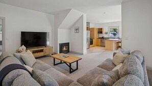 Moderni olohuone, jossa on suuri televisio, takka ja sohva.