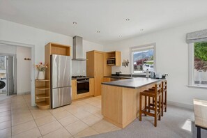 A modern kitchen with a central island, stainless steel appliances, and wooden cabinetry.
