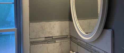 A bathroom with a white sink, a mirror, and a window.