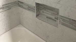 Un baño con paredes de mármol y piso de baldosas.