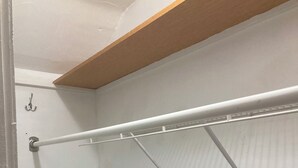 Un armario abierto con un perchero metálico y un estante de madera encima.