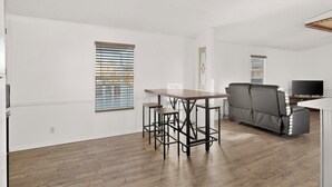 Een moderne woonkamer met een bank, een eettafel met stoelen en een televisie.