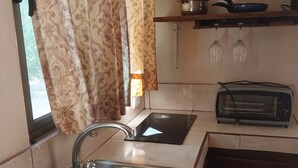 A kitchen with a sink, a toaster, and a window with curtains.