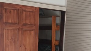 A bedroom with a bed, a wooden wardrobe, and a sliding door leading to a closet.