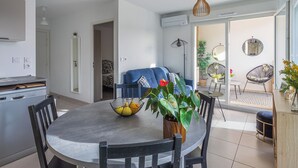 Ett modernt kök med en matplats, en blå soffa och en balkong med växter och en stol.