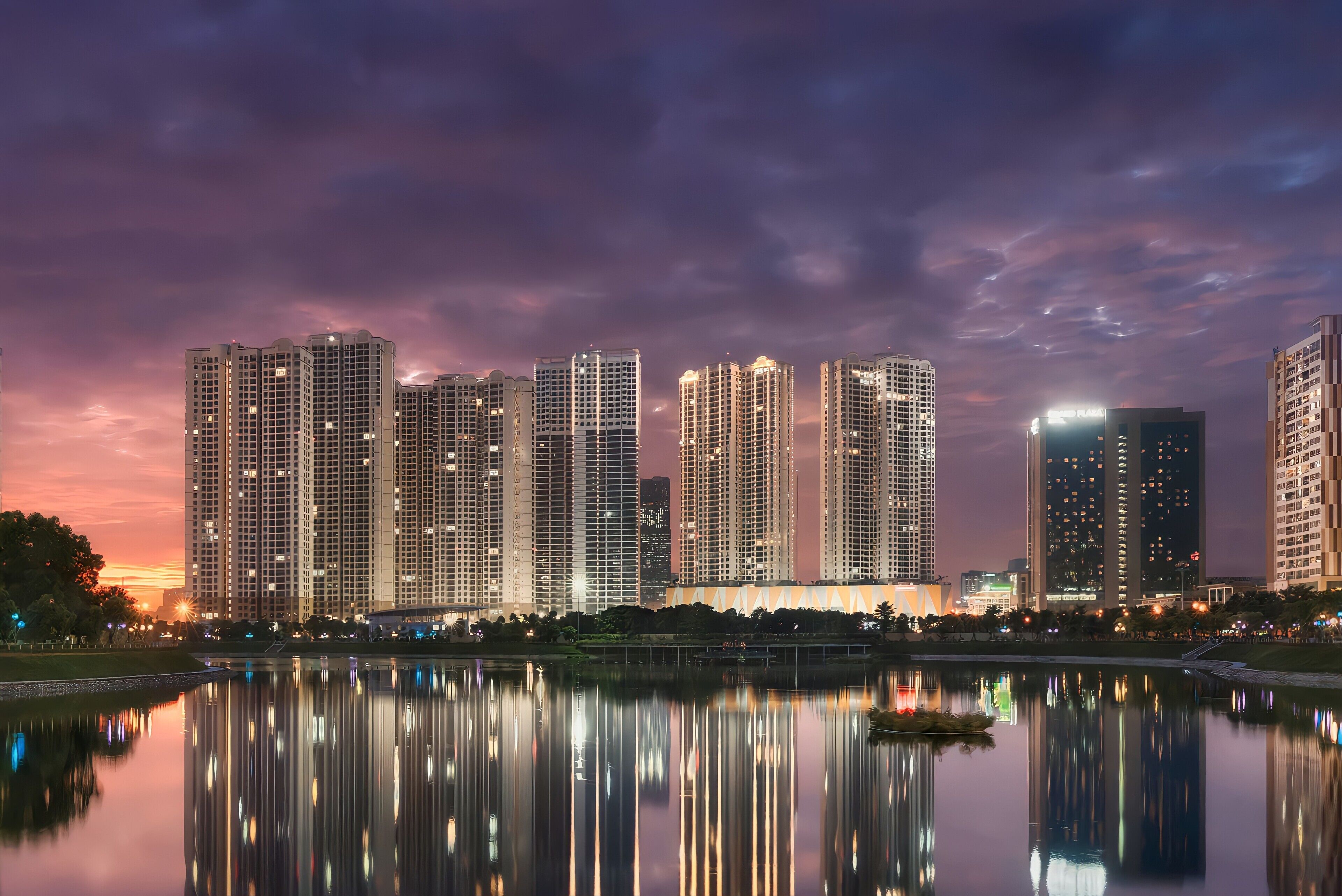 Un horizonte urbano con rascacielos, una masa de agua tranquila que refleja los edificios, y un cielo despejado.