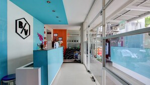 Un espace d’accueil avec un comptoir bleu, un logo sur le mur et une vue à travers une porte vitrée.