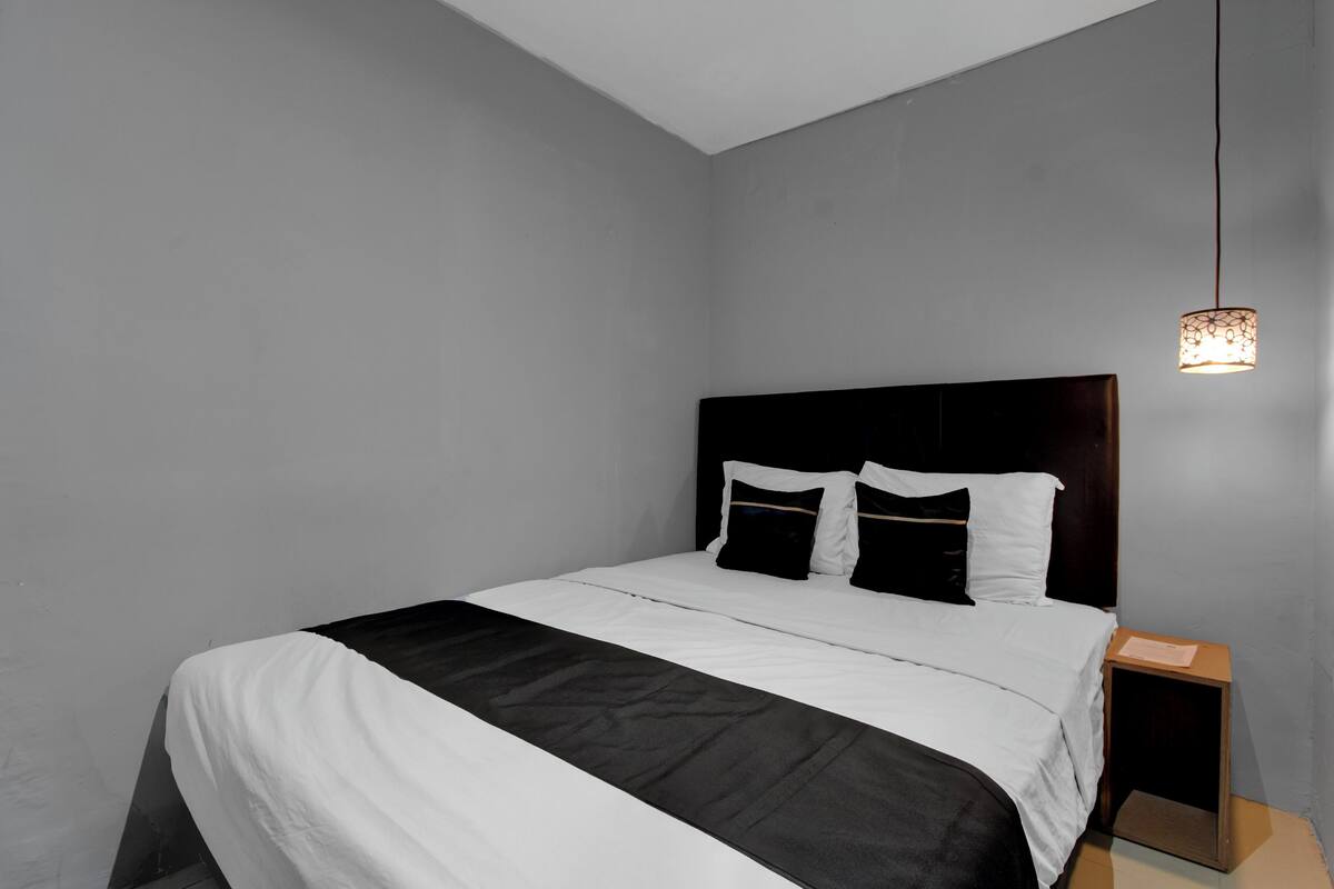 A modern bedroom with a large bed, a wooden nightstand, and a hanging light fixture.
