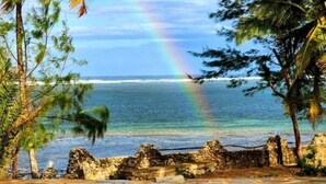 A tropical resort with a pool, palm trees, and a view of the ocean. - Duplex Ocean View 1bedroom Apartment D10 ,Top Floor (Mombasa)