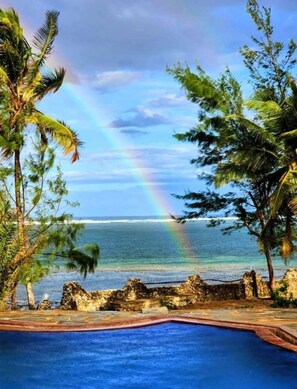 Ein tropisches Resort mit Pool, Palmen und Blick auf das Meer.