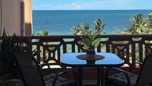 A balcony with a table and chairs, overlooking a clear blue sea and palm trees. - Duplex Ocean View 1bedroom Apartment D10 ,Top Floor (Mombasa)