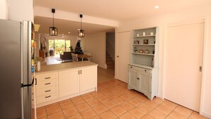 Una cucina con mobili bianchi, un frigorifero e un'area pranzo con tavolo e sedie.