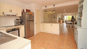 Una cucina moderna con mobili bianchi, un frigorifero in acciaio inossidabile e un pavimento piastrellato.