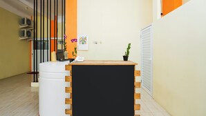 Un área de recepción con un mostrador de madera, una planta en maceta y un calendario de pared.